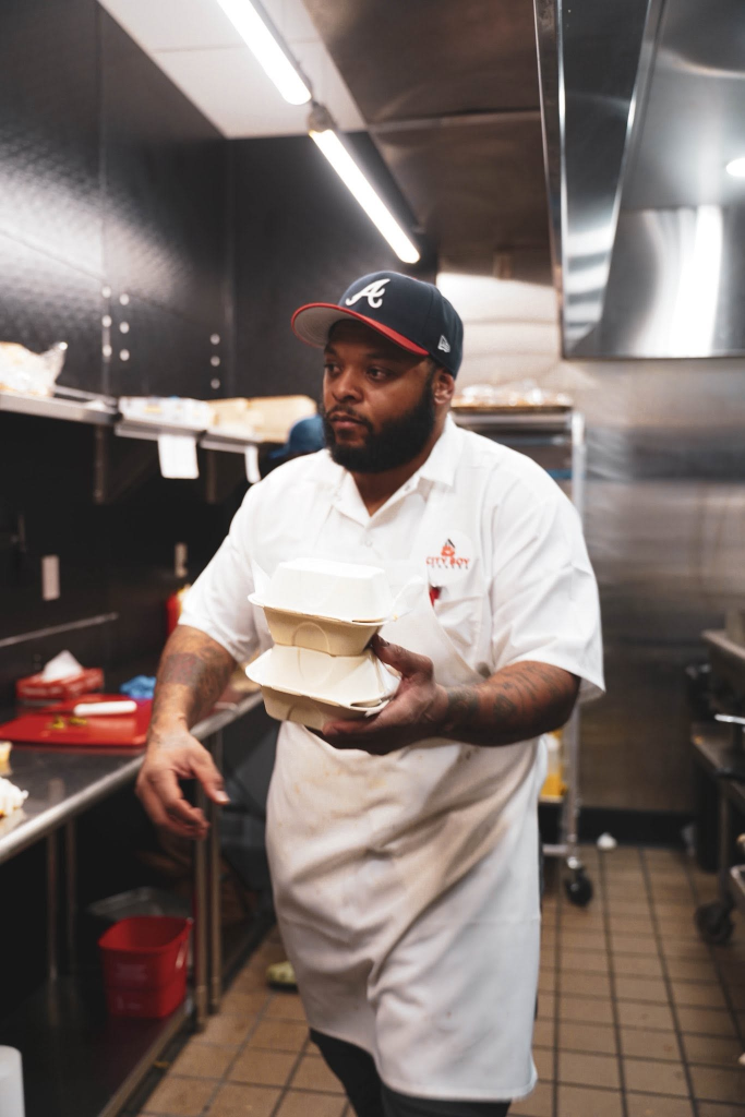 City Boy Burgers Head Chef carrying fresh takeout orders in the kitchen